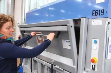 kvinna stänger luckan på en elektrisk balpress