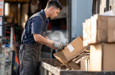 Man som lägger en kartong i en behållare