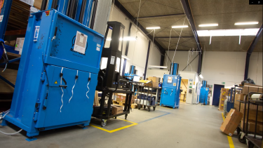 Tre blå balpressar placerade i produktion hos Hydra Specma