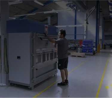 Man i tillverkningsmiljö som använder en stor Mil-tek-balpress