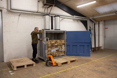 Man som använder en tryckluftsdriven balpress