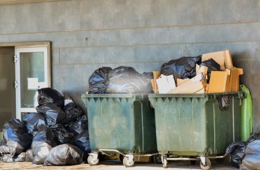 Utomhus gröna avfallscontainrar som svämmar över av avfall