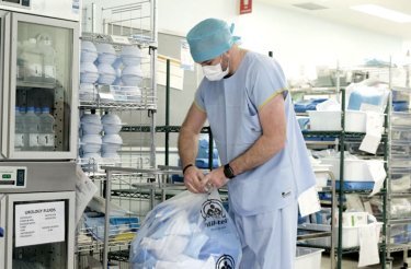 man-i-läkarkläder-hanterar-säck-med-sjukhusavfall